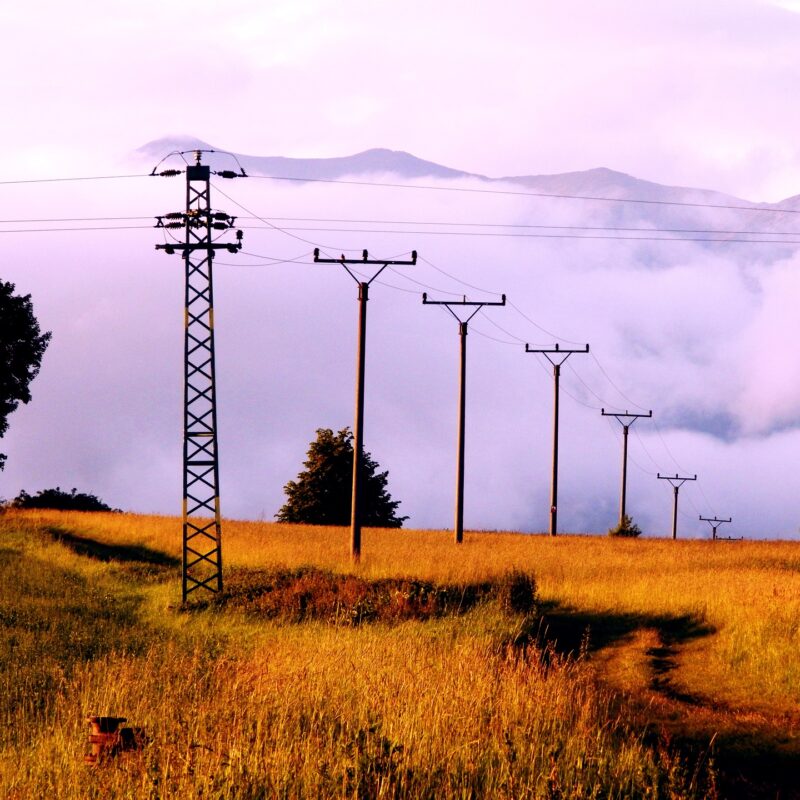 A picture showing electrical pylons spreading out across an open field, a reminder of the need for safely grounding electricity