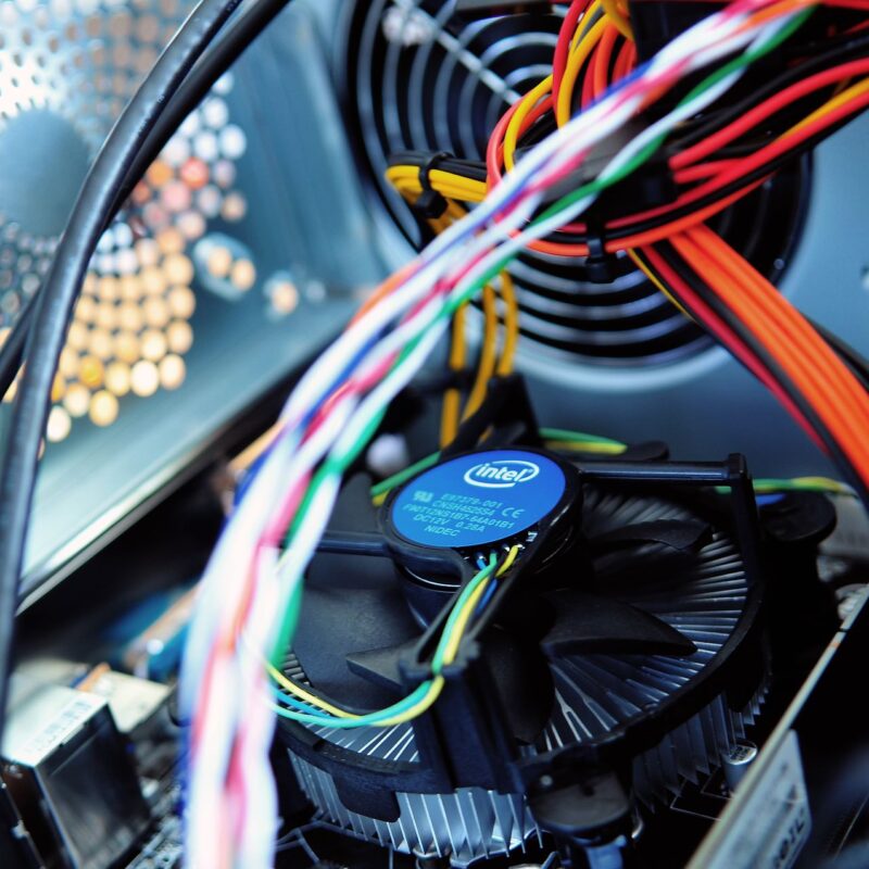 A picture showing wires and a fan inside of a computer, parts of equipment that are checked in electrical testing