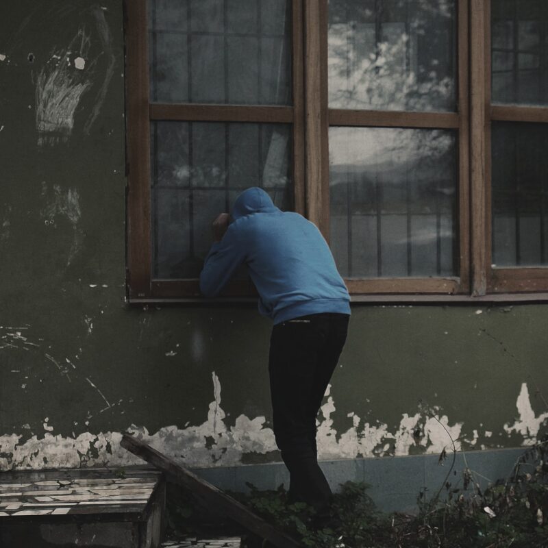 A picture of burglar looking into a house without an intruder alarm or home security