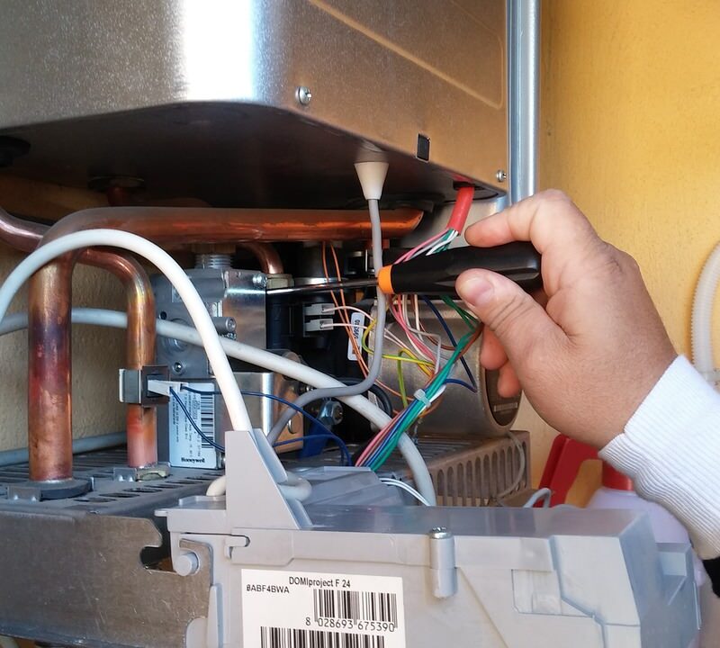 A picture of a man fixing electric boiler problems