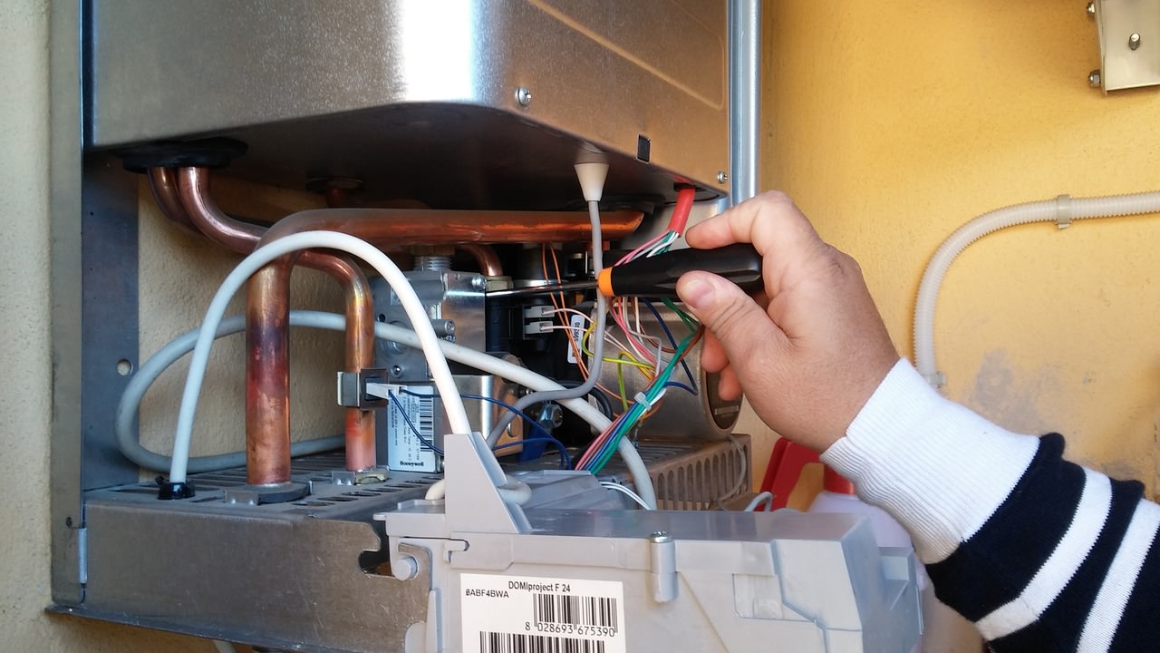 A picture of a man fixing electric boiler problems