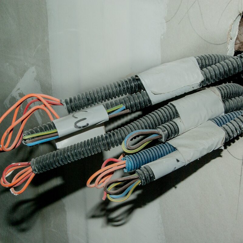A picture of wires coming out of a wall, part of a routine inspection done for electrical test certificates