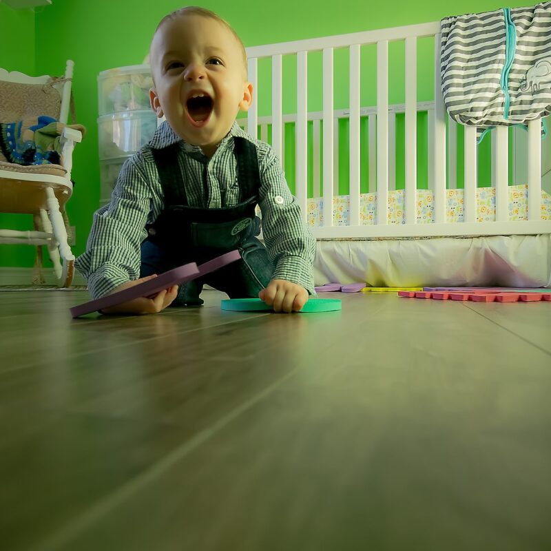 A picture of a toddler in his playroom, one of the places that you should remember when baby proofing your home against the risk of electric shock